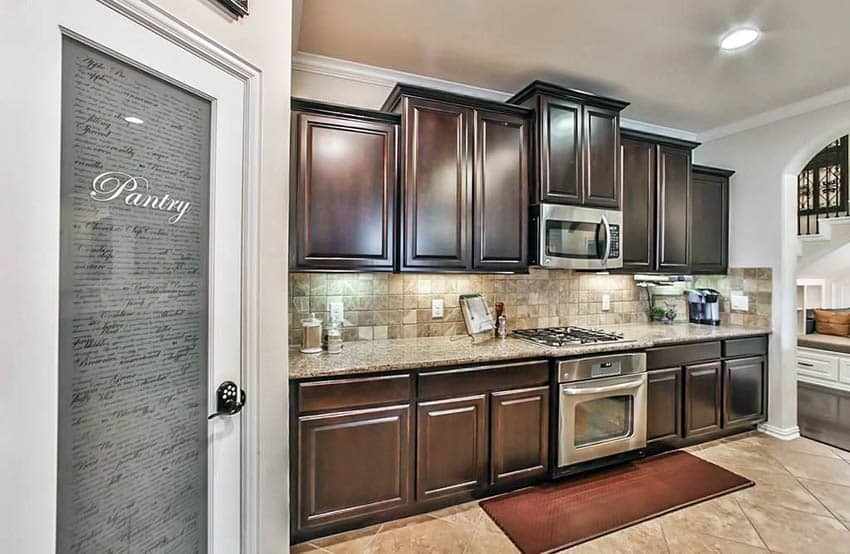 Small one wall kitchen with dark cabinets travertine backsplash and large pantry