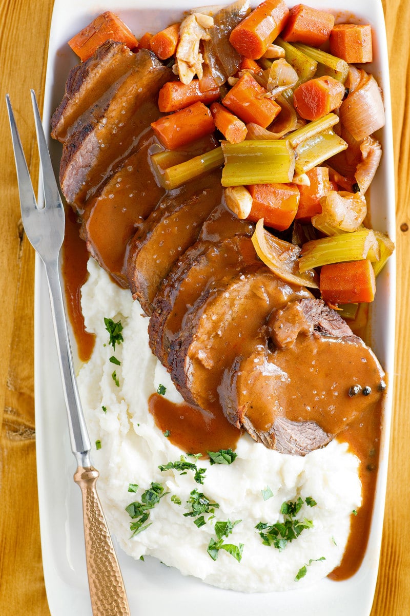 Merlot Pot Roast sliced with sauce and served with vegetables and horseradish mashed potatoes